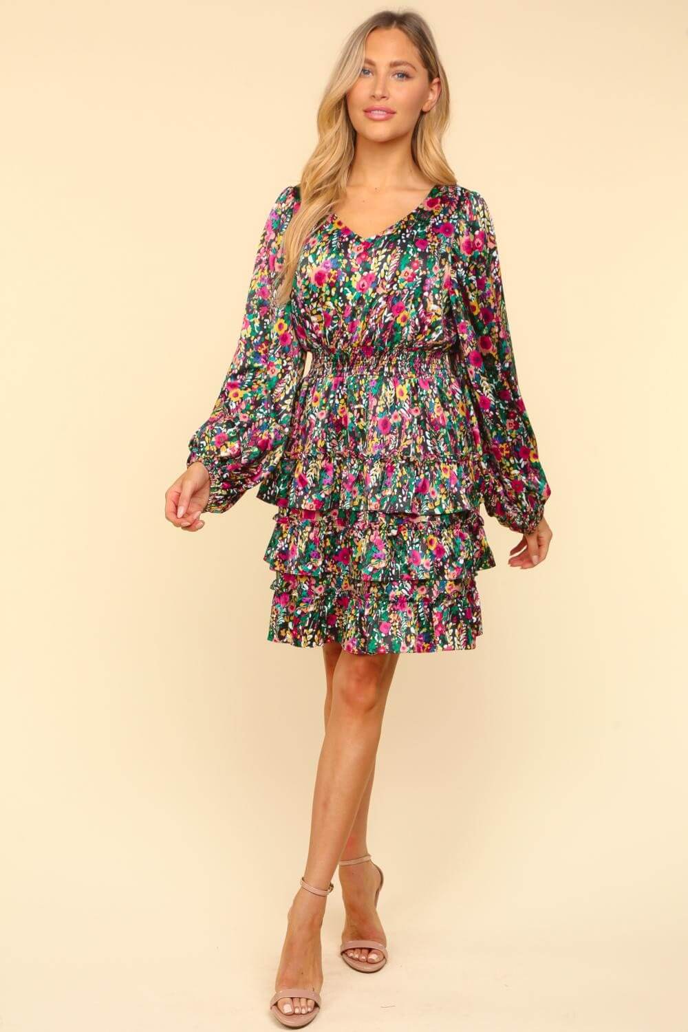 Woman wearing a floral layered dress with a V-neckline, showcasing vibrant colors and an elegant silhouette.