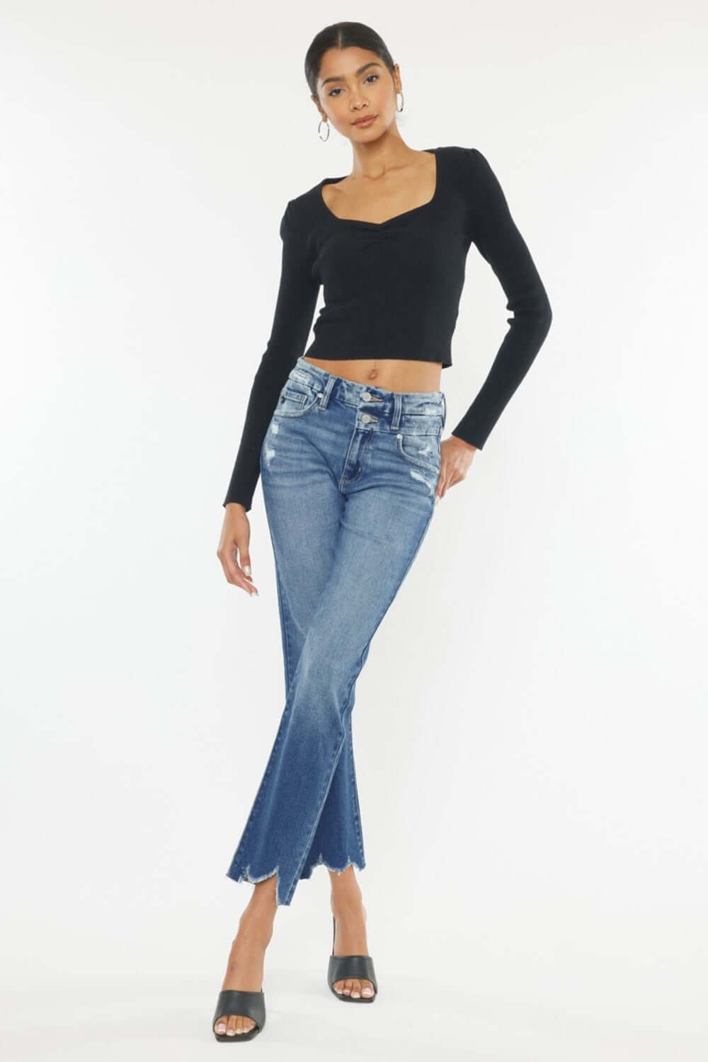 Woman modeling Kancan High Rise Wide Waistband Slim Straight Jeans with frayed hem and stretchy denim in medium stone wash.