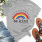 Gray round neck short sleeve t-shirt with rainbow and 'be kind' text, paired with jeans and sandals for a casual look.