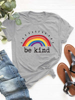 Gray round neck short sleeve t-shirt with rainbow and 'be kind' text, paired with jeans and sandals for a casual look.