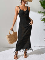 Woman wearing an openwork scoop neck cover-up dress with tassels and holding a woven handbag.