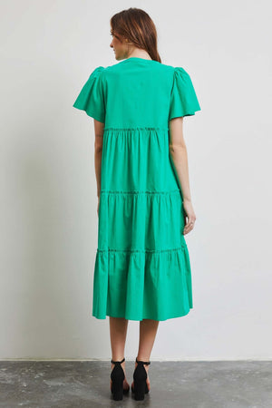 Woman wearing HEYSON green cotton poplin ruffled tiered midi dress, showcasing back view and elegant flowy design.