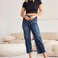 Woman wearing Tummy Control High Waist Raw Hem Jeans by RFM Jeans in a living room.