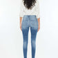 Woman wearing high rise frayed ankle skinny jeans in medium wash with a white top, showcasing back view of the denim’s fit and style