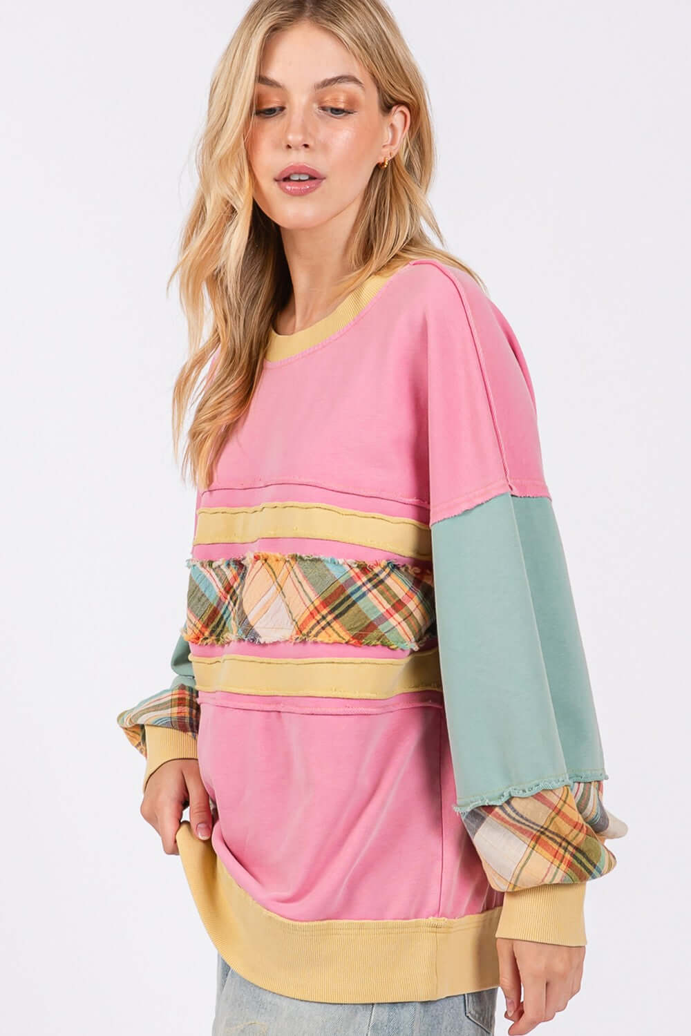 Woman wearing a Mineral Wash Raw Edge Color Block Sweatshirt with plaid print contrast sleeves and French Terry fabric for a trendy look