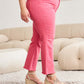 Woman wearing pink RFM Jeans with high waist and raw hem, showing belly control feature and stylish slender leg line.