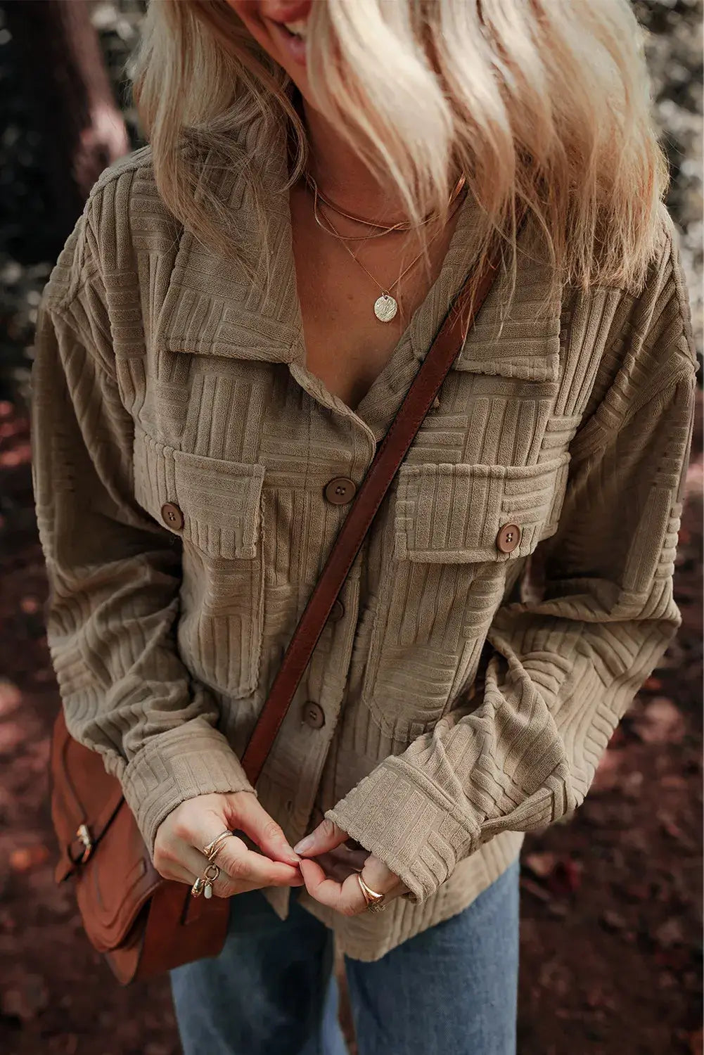 Woman wearing a textured beige shacket with pockets, collared neck, and long sleeves.