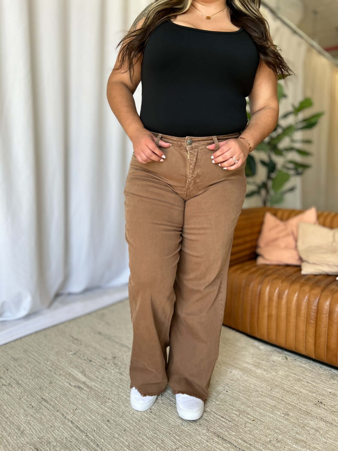 Woman wearing RFM Full Size High Rise Garment Dye Wide Leg Jeans in brown, standing in a stylish setting with a casual top.