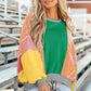 Woman wearing Bella Road Color Block Round Neck Long Sleeve Top with green, pink, and yellow sections, standing outdoors.