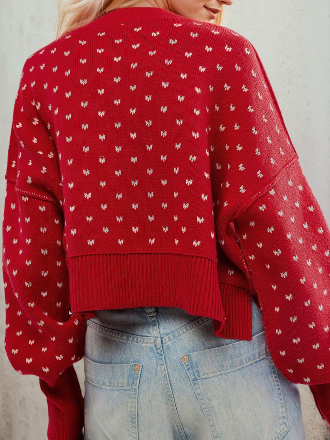 Woman wearing red sweater with small white heart pattern, showcasing cozy fall fashion paired with light blue jeans.