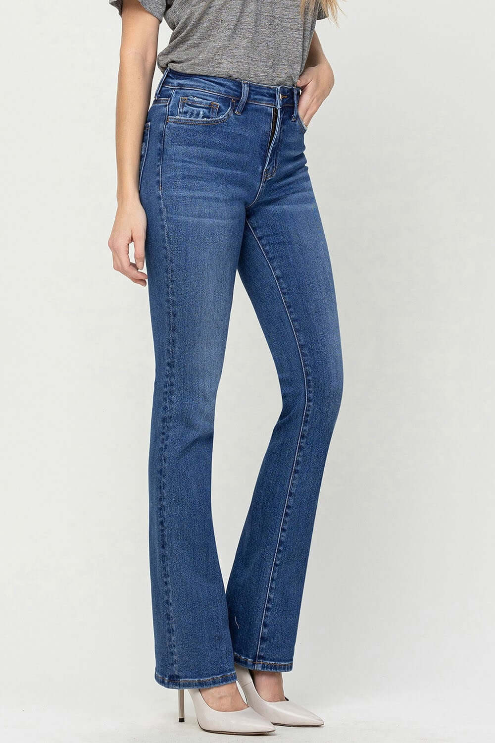 High Waist Bootcut Jeans in blue denim worn with a casual grey top and white heels.