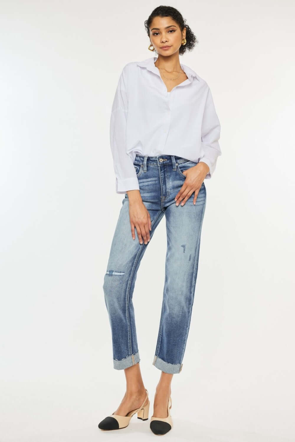 Woman wearing high rise cuffed straight jeans with white blouse and heels