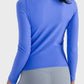 Back view of a woman wearing a blue Millennia Round Neck Long Sleeve Sports Top, showcasing its stylish design and fit.