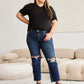 Woman wearing Crop Dylan Full Size Tummy Control Distressed High Waist Raw Hem Jeans by RFM Jeans, standing in a stylish living room.