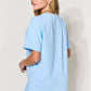 Woman wearing light blue graphic round neck short sleeve t-shirt from back view, paired with blue jeans.