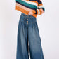 Woman wearing SAGE+FIG smocked waist wide leg jeans with striped sweater and hat. Fashionable and comfortable style.