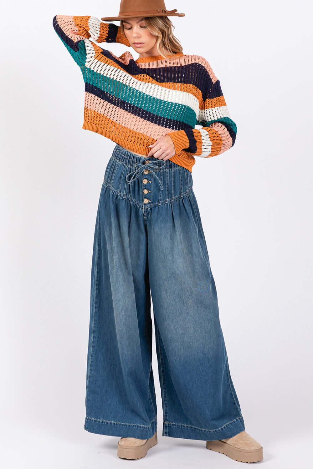 Woman wearing SAGE+FIG smocked waist wide leg jeans with striped sweater and hat. Fashionable and comfortable style.