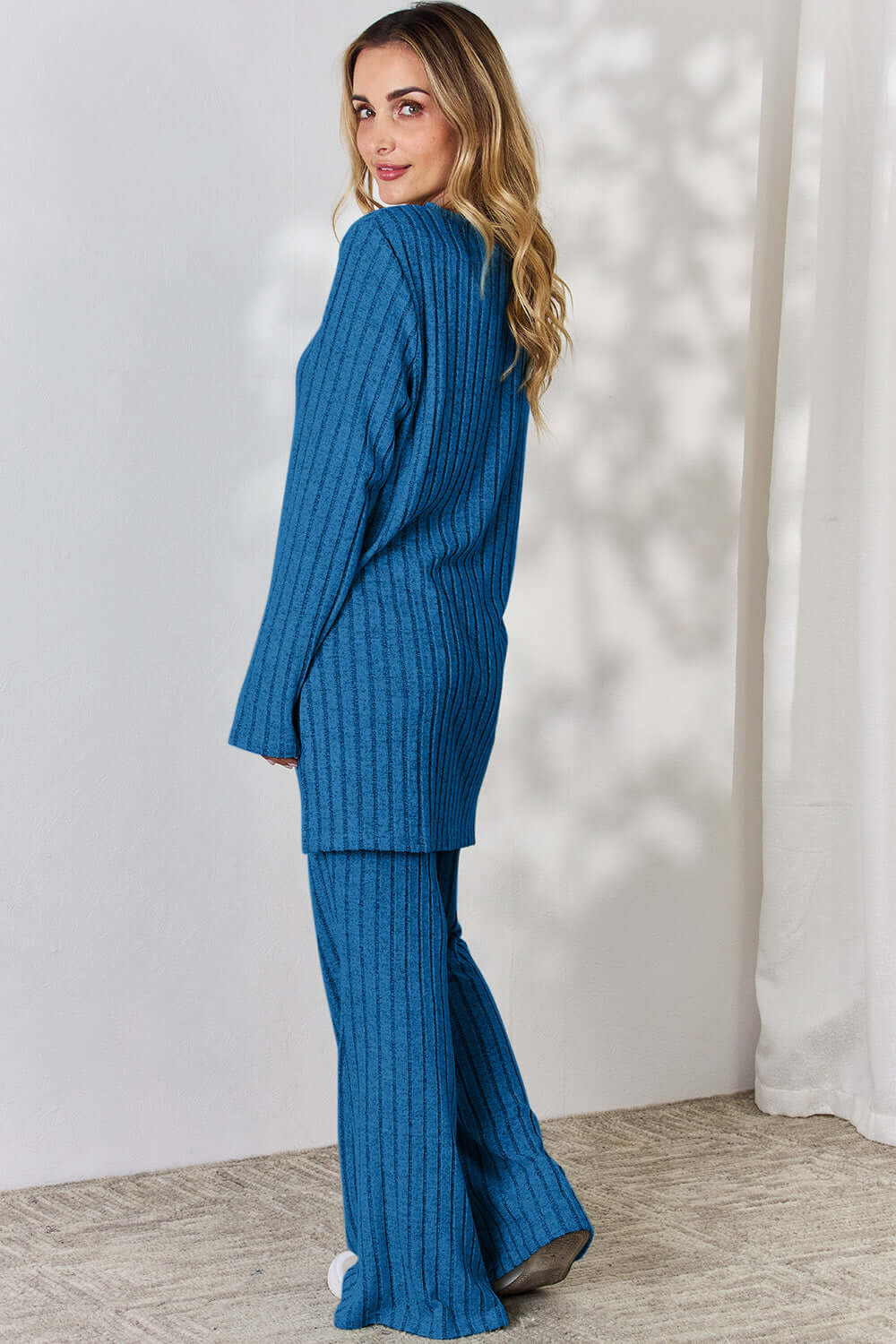 Woman wearing Ribbed High-Low Top and Wide Leg Pants Set in blue, shown from the back, featuring slightly stretchy fabric and long sleeves.