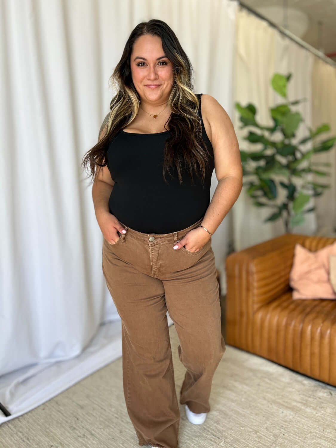 Woman wearing RFM High Rise Garment Dye Wide Leg Jeans in rich brown, standing in a stylish room with a chic and relaxed vibe.