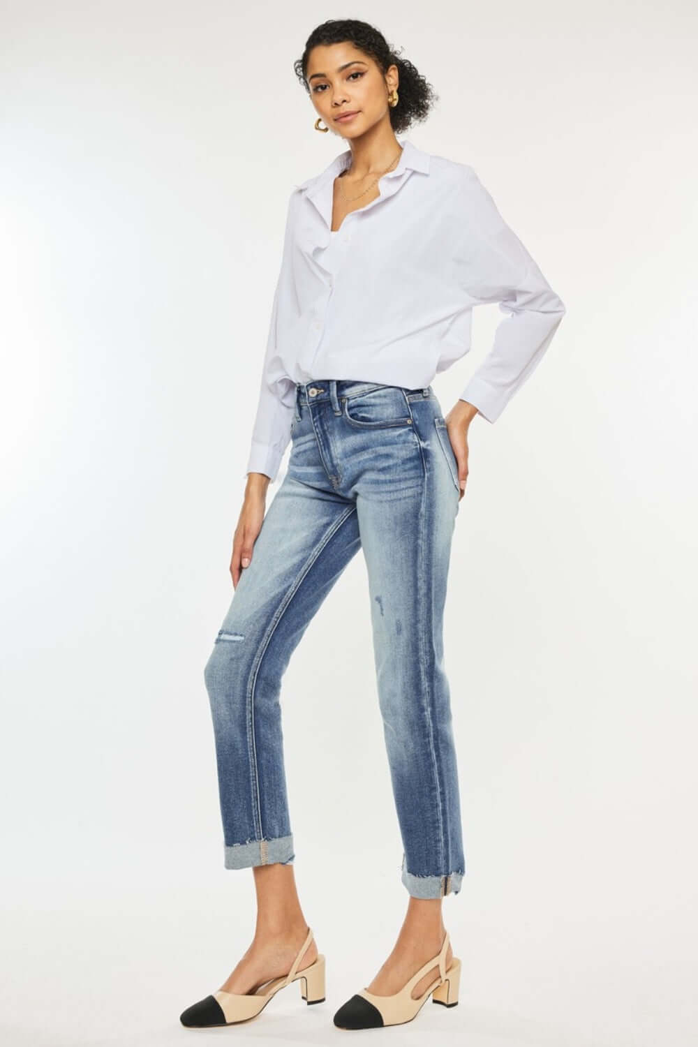 Woman wearing high rise cuffed straight jeans with a white blouse and heels