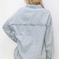 Back view of a woman wearing a light denim button-up long sleeve shacket from Risen Jeans.