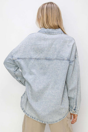 Back view of a woman wearing a light denim button-up long sleeve shacket from Risen Jeans.