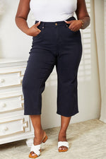 Woman wearing high-waist tummy control garment-dyed wide cropped Judy Blue jeans in black.