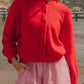 Model in a cozy red Bella Road Button Down Cardigan paired with striped shorts on a sunny beach day.