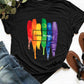 Black graphic round neck short sleeve t-shirt with "Love Wins" rainbow paint stroke design, displayed with jeans and sandals.