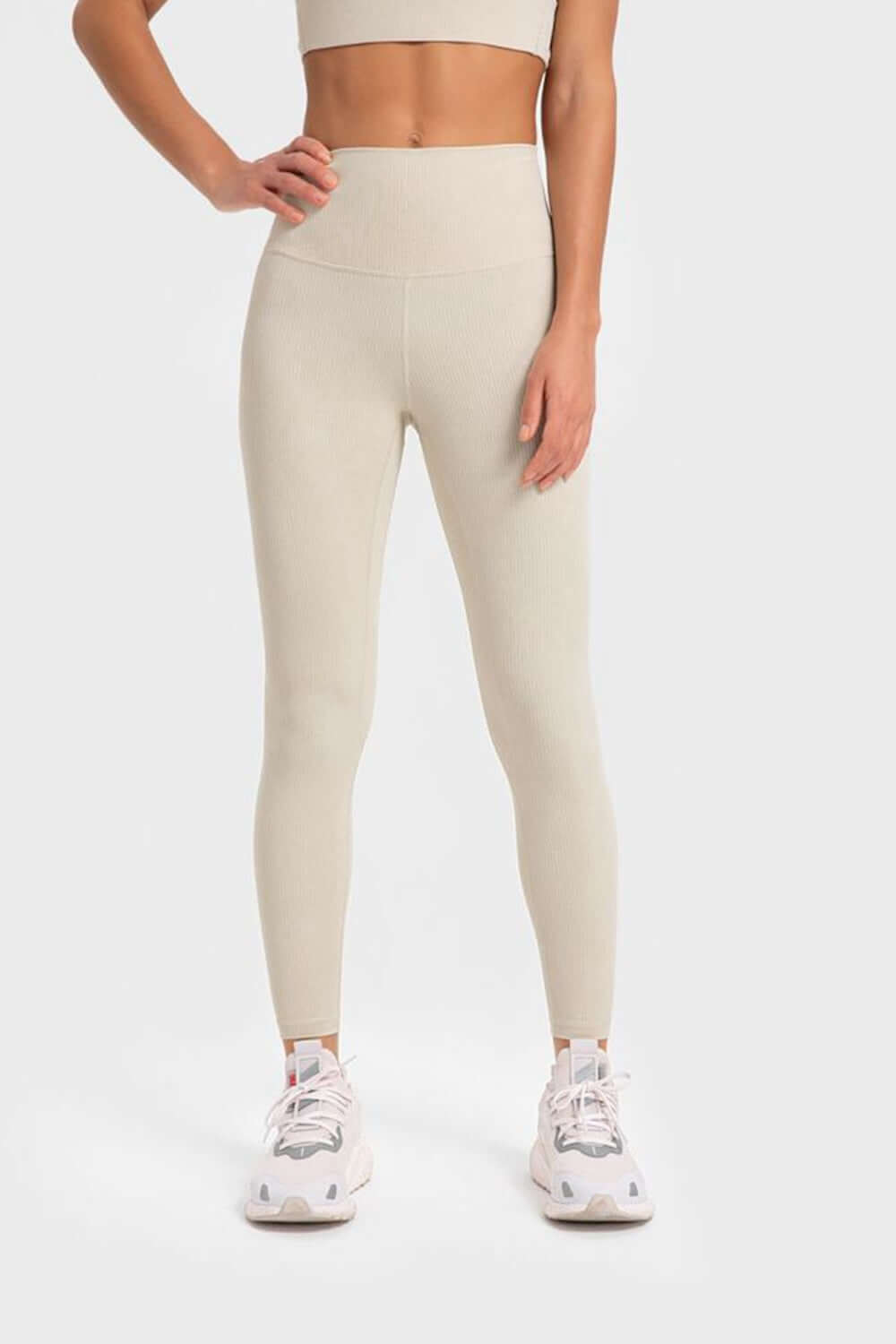 Woman in beige Millennia Highly Stretchy Wide Waistband Yoga Leggings, styled with a crop top and athletic shoes.