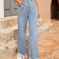 Light wash bootcut jeans with raw hem on a stylish model, showcasing pockets and a trendy outfit.