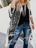 Chic woman in Bella Road Swim Printed Cover-Up over black top and ripped jeans, perfect for beach style.