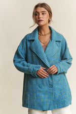 Woman models a blue tweed double-breasted coat with long sleeves, showcasing its elegant and sophisticated design.