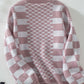 Dusty pink checkered open front cardigan with dropped shoulders, displayed on a hanger. Stylish and playful knitwear.