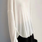 White high-low long sleeve T-shirt in sheer fabric with slightly stretchy fit, paired with black bottom; stylish and comfy look.