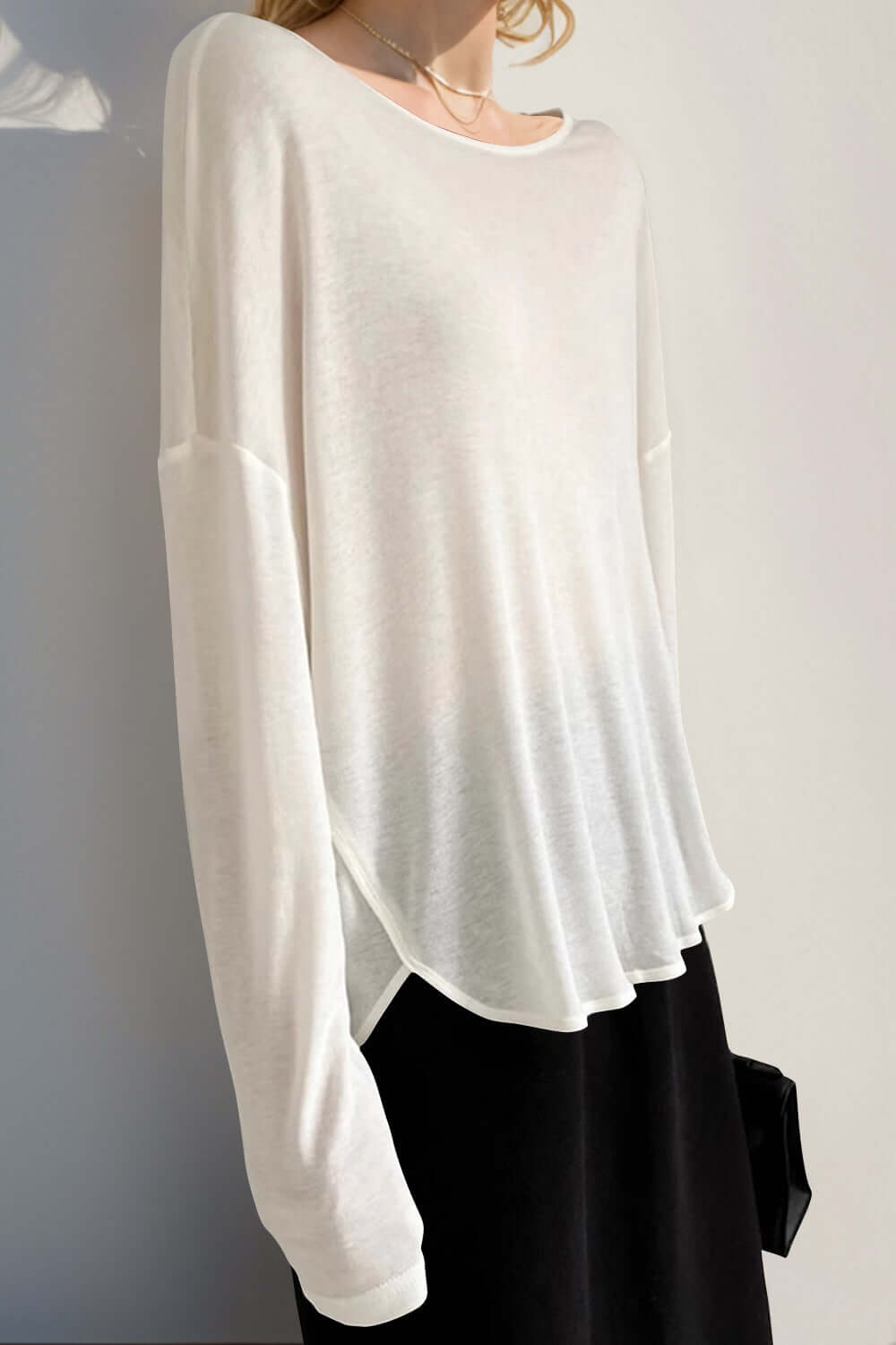 White high-low long sleeve T-shirt in sheer fabric with slightly stretchy fit, paired with black bottom; stylish and comfy look.