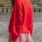 Model wearing a cozy red Bella Road Button Down Cardigan by the beach, paired with striped shorts. Ideal for chilly days!