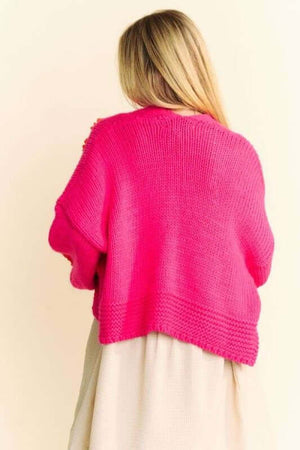 Stylish woman in a vibrant pink cardigan, showcasing the cozy drop shoulder design from the back. Perfect for layering!