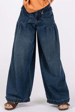 Mid-rise wide-leg jeans with dropped front patch pockets and cinch-tie banded ankles, worn with an orange top and sandals.