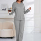 Woman in gray Bella Road hoodie and pants set, holding coffee, in stylish lounge setting.