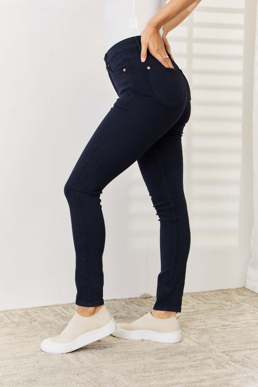 Judy Blue Garment Dyed Tummy Control Skinny Jeans in dark wash worn with white sneakers for a slimming silhouette.