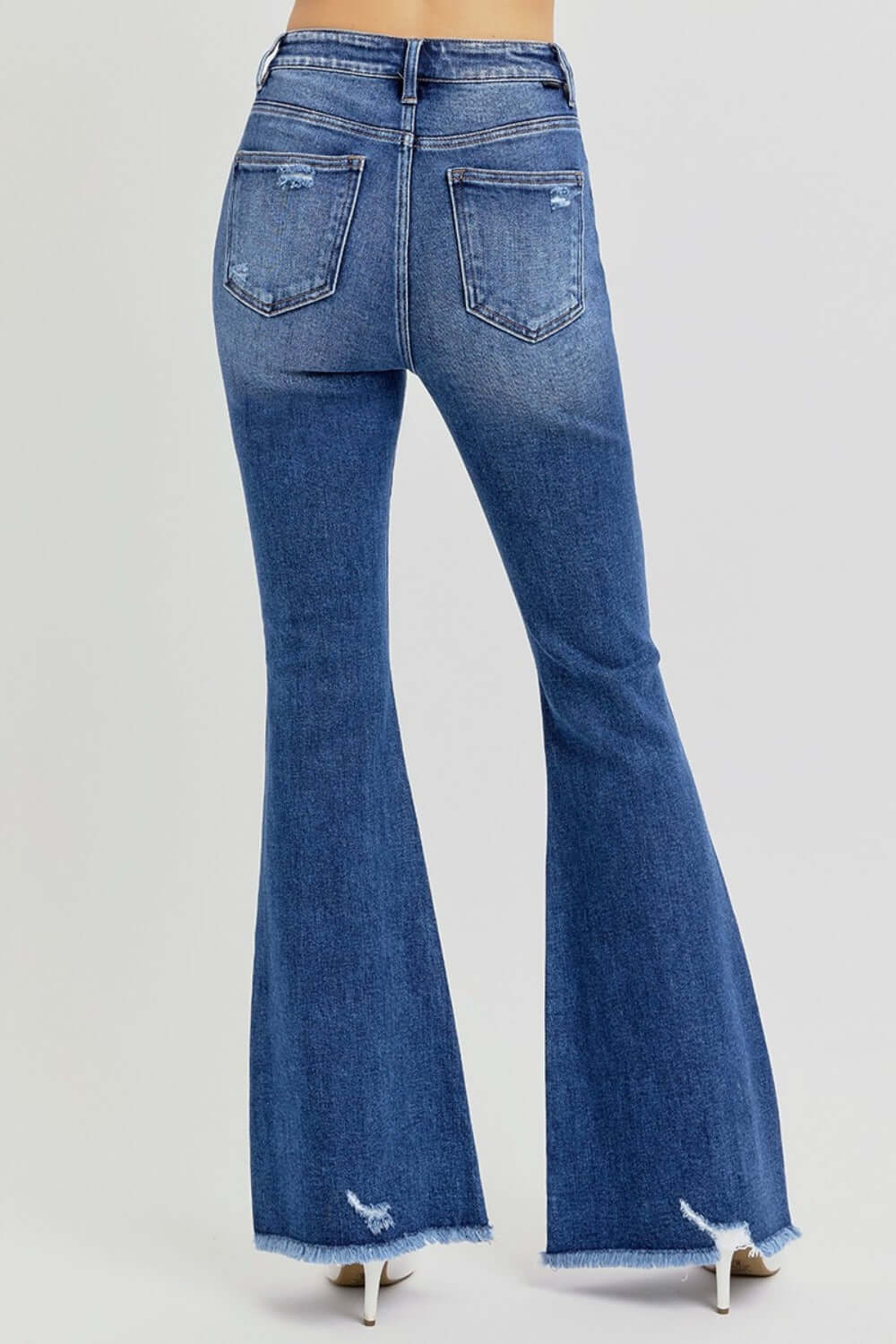 High rise distressed raw hem flare jeans showcasing a trendy and stylish retro vibe with flare legs and modern detailing.