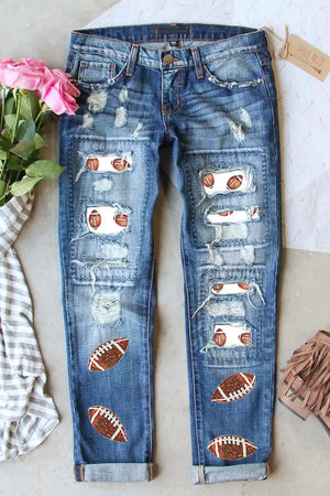 Distressed Football Straight Jeans with Sporty Patches on Distressed Areas, Laid Flat with Pink Flowers and Fringe Accessories