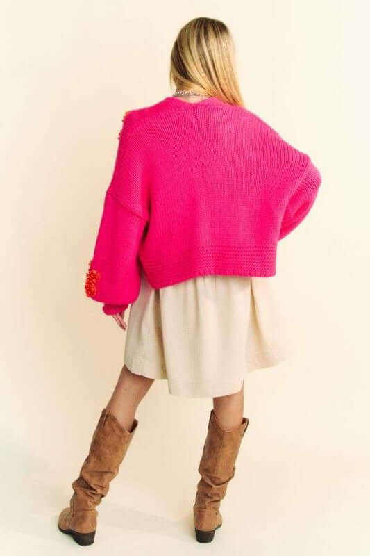 Model wearing a vibrant pink open front drop shoulder cardigan over a cream dress, showcasing a relaxed style.