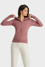 Woman in a pink zip-up hooded sports jacket, styling the comfortable and versatile Millennia jacket for outdoor activities.