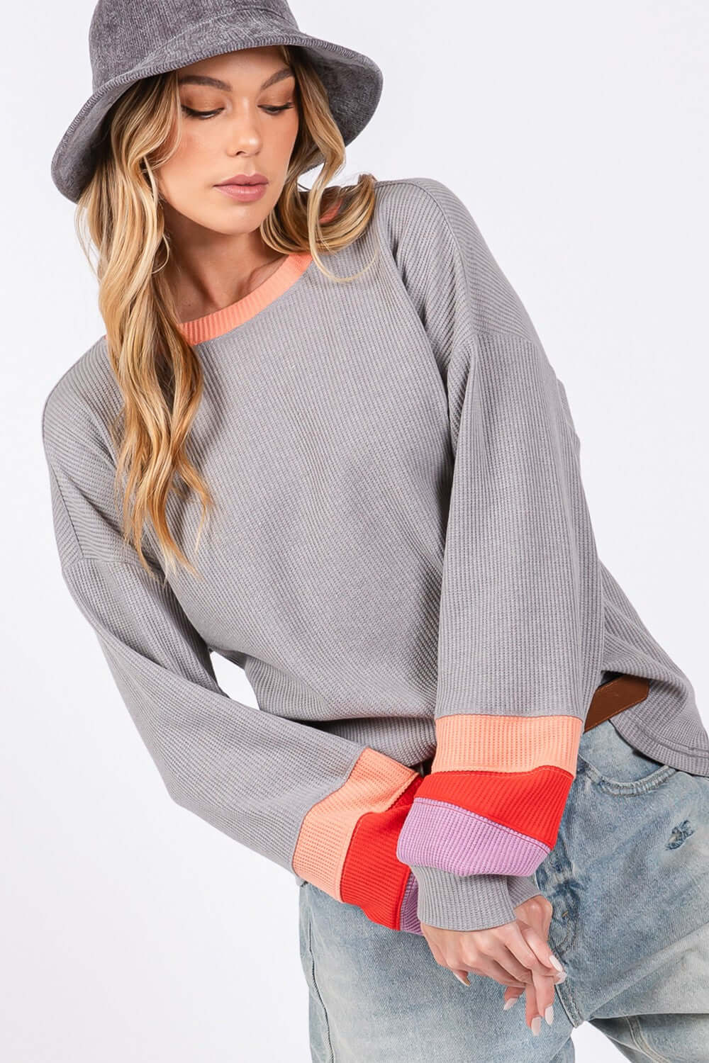 Woman wearing a Color Block Waffle Knit T-Shirt with raglan sleeves, contrast crew neckline, and trendy color-blocked long sleeves for a casual look.