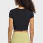 Back view of a woman wearing a black cropped sports t-shirt paired with light green yoga pants. Perfect for workouts!