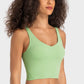 Model showcasing the Millennia Deep V-Neck Crop Sports Bra in vibrant green, perfect for stylish workouts and comfort.