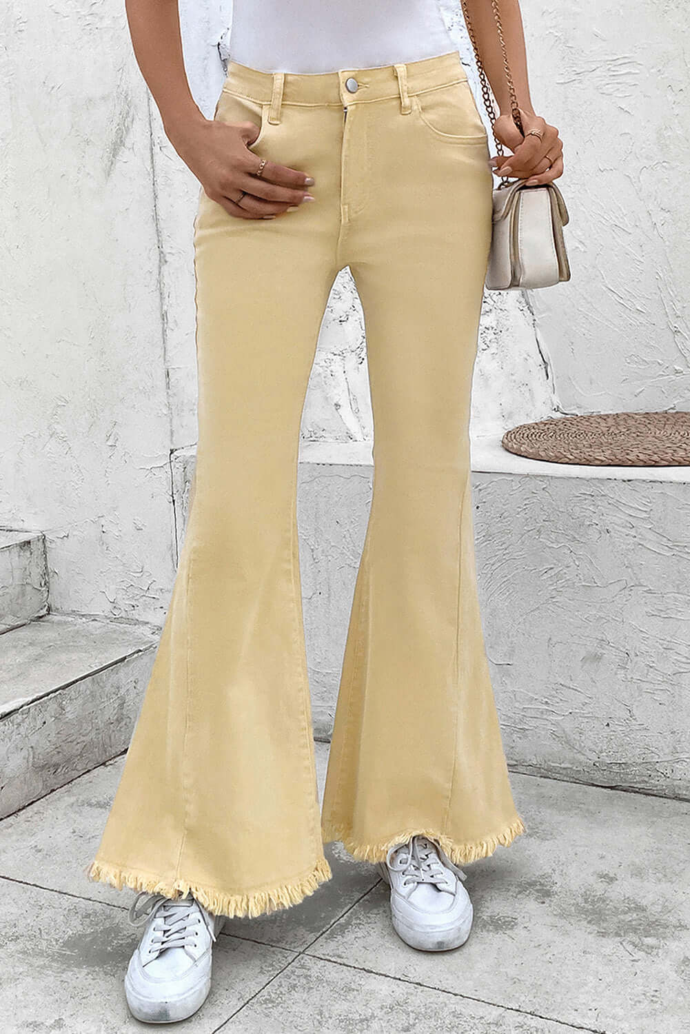 Woman wearing Bella Road Pocketed Raw Hem Flare Jeans in mustard yellow with white sneakers and a white top