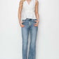 Woman wearing mid-rise bootcut jeans and white sleeveless top, showcasing Risen Jeans with a classic flared silhouette for versatile styling.